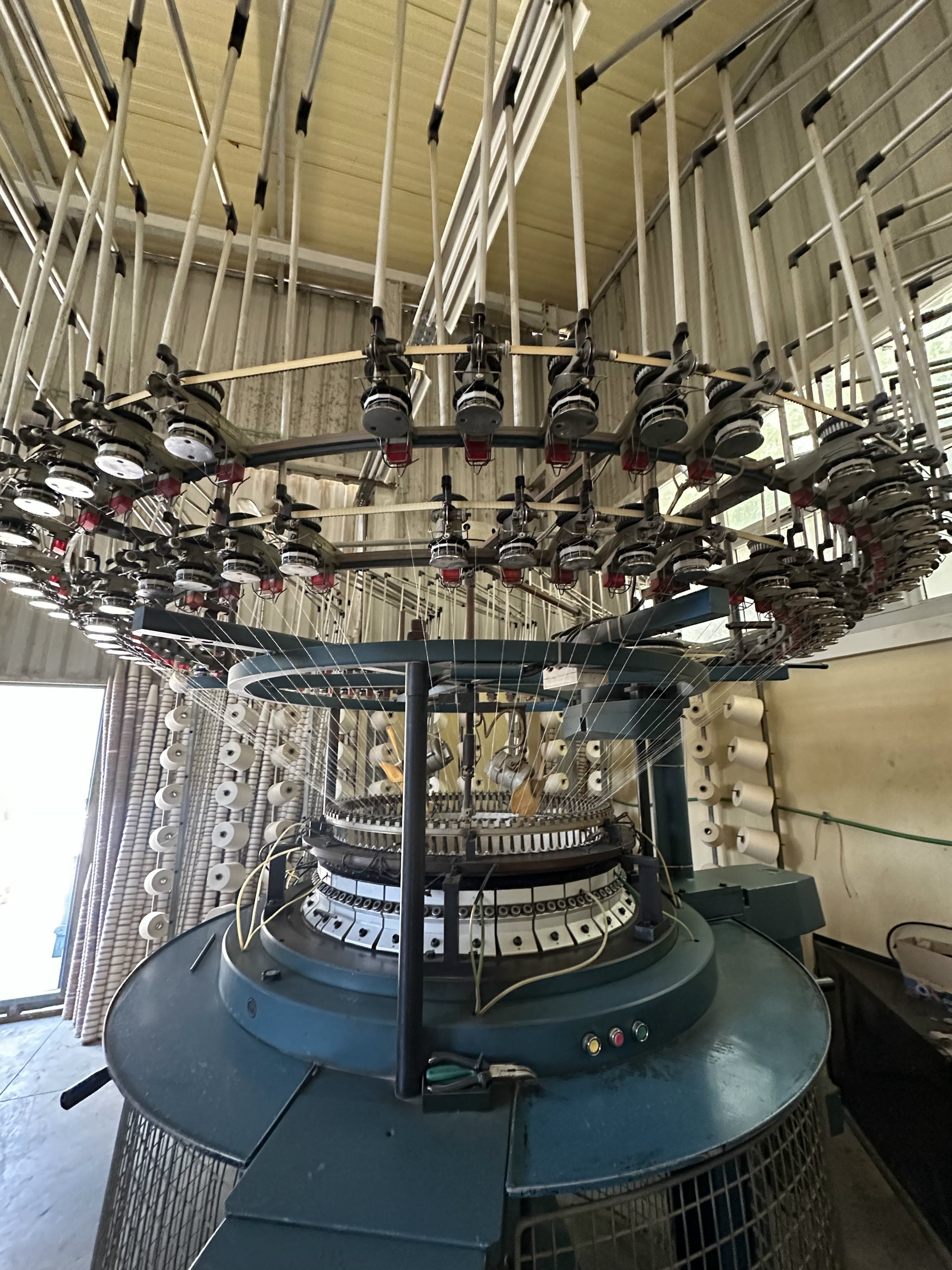 Looking up into a circular knitting machine and its yarn feeders